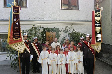 Die Erstkommunionkinder des heurigen Jahres, die Ministranten, P. Daniel Gärtner sowie die Fahnenträger der Feuerwehren Limbach und Sallingstadt vor dem Altar bei Familie Kaufmann