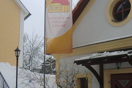 Der Eingangsbereich des Dorfhaus mit dem Osterstrauß und der Fahne "Unser Haus wird 100"
